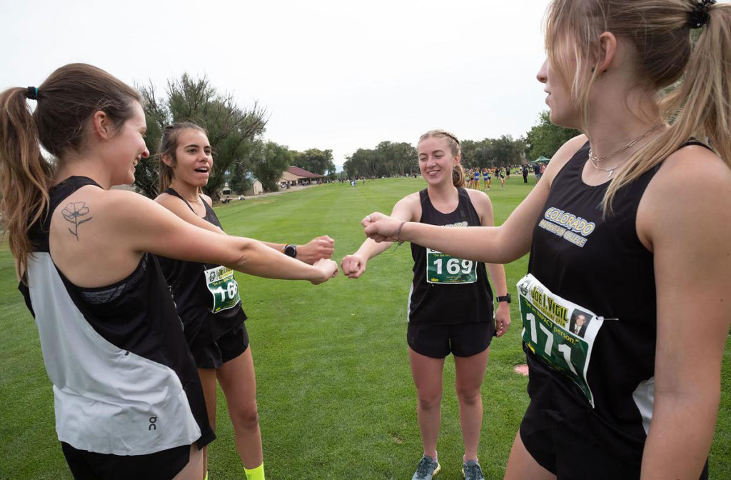 CMC women's cross country team fist bump before a race