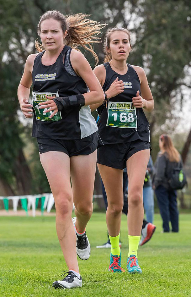 Two CMC CMC women cross country teammates running on course.